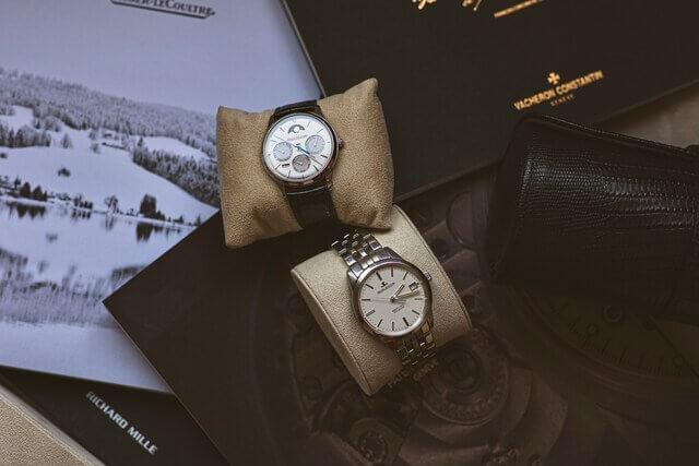 2 Montres de luxe à côté d'un coffret et d'un livre